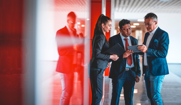 three-people-in-office-setting-discussing-over-documents-bdo