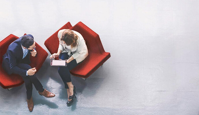 couple-sitting-on-designed-red-furniture-working-on-tablet-bdo