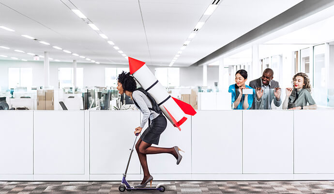 girl-on-heels-scooting-in-office-holding-rocket-backpack-fun-bdo=eaton-square